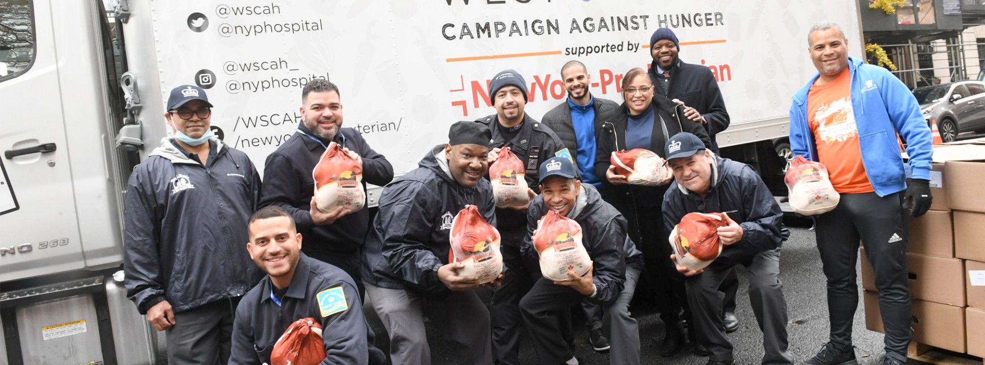 A group of Facilities and Operations employees stand in front of a delivery truck that contains donated turkeys from Facilities and Operations