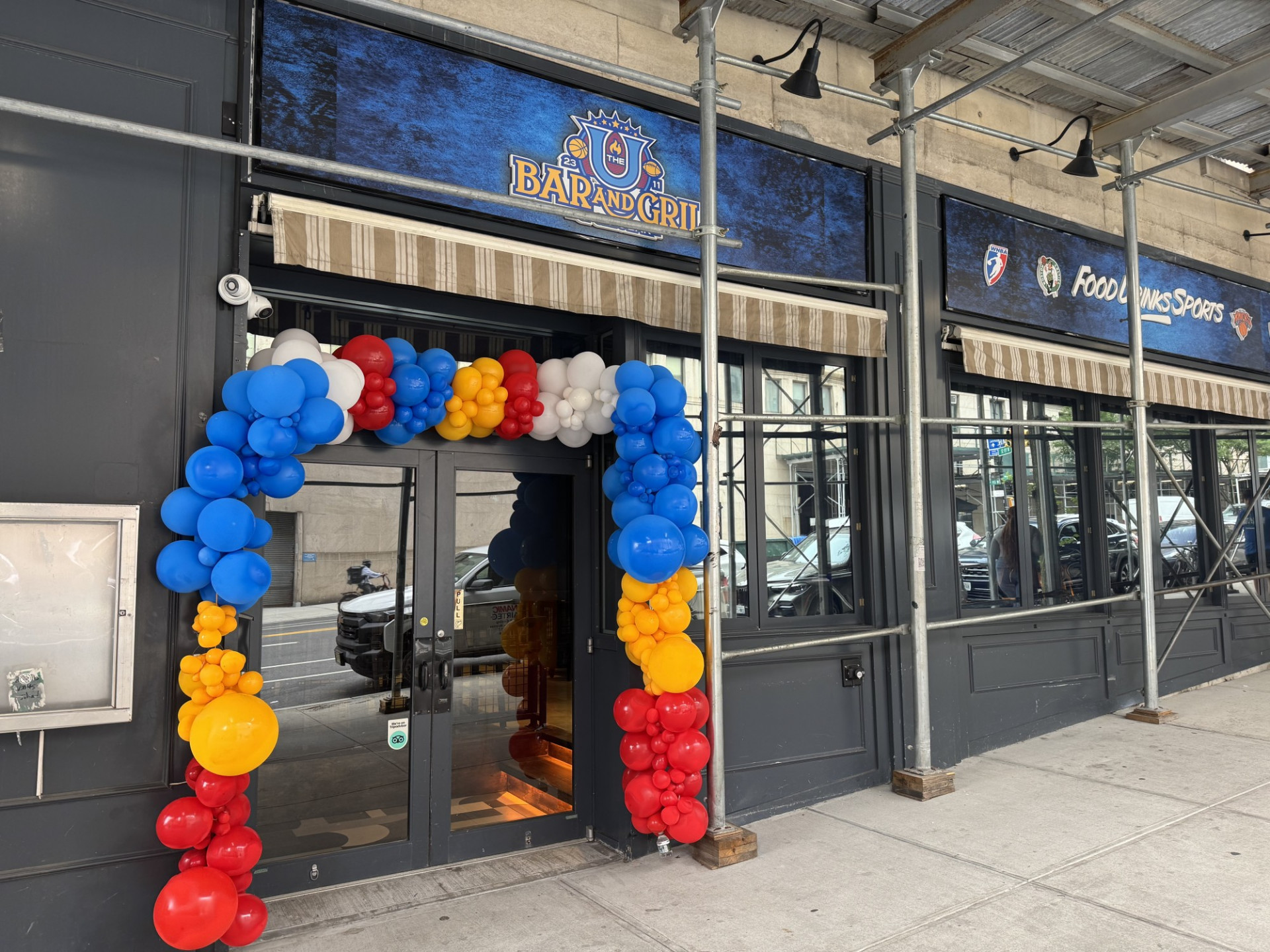 The entrance to The U Bar and Grill restaurant, that has a blue sign and balloons over the doorway.