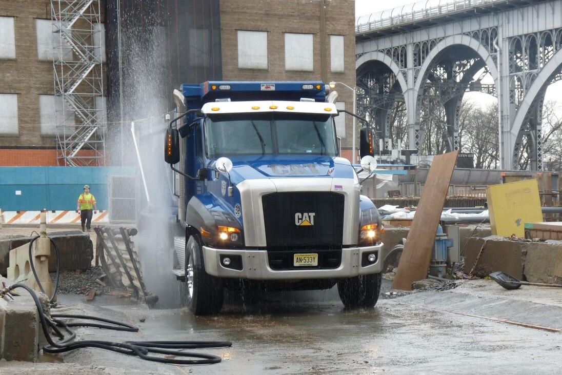 A large pickup truck is getting its wheels powerwashed at the Manhattanville campus construction site 