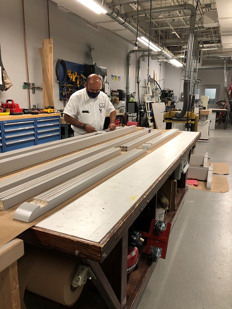 A painter from the Manhattanville Operations team applies paint to the frames. A painter applies a coat of silver paint to the tops and bottoms of the frames.