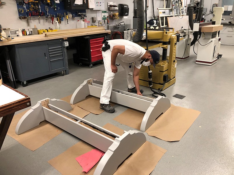 A painter from the Manhattanville Operations team applies paint to the bases of the frames. A painter applies a coat of silver paint to the tops and bottoms of the frames.