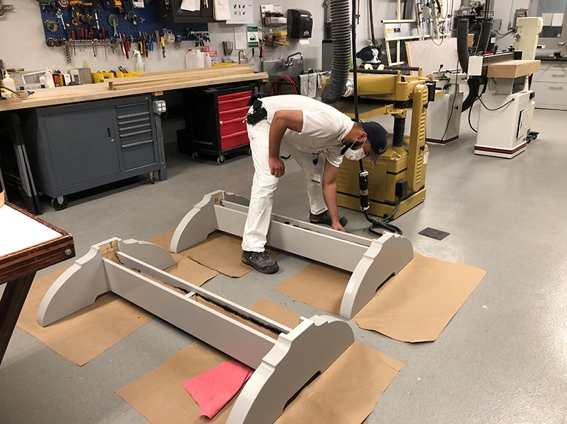 A painter applies a coat of silver paint to the tops and bottoms of the frames.