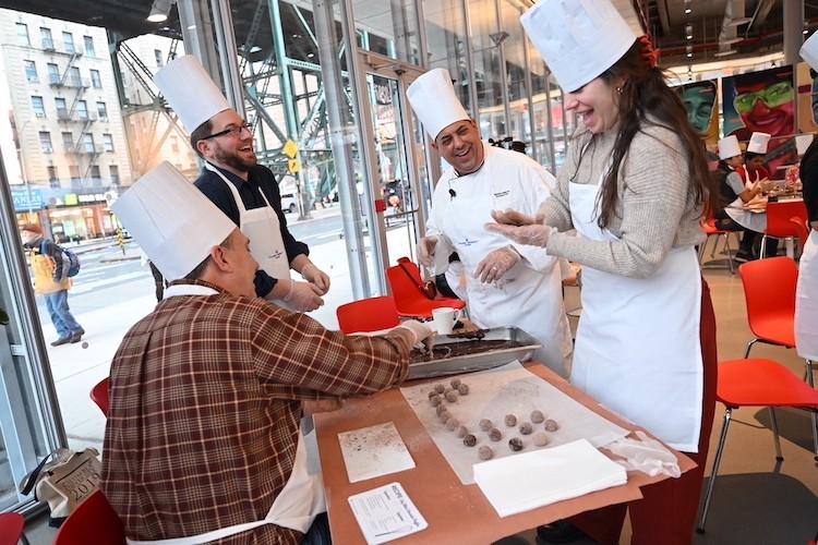 Chef Mike helps people wearing aprons and chef hats make truffles.