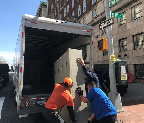 three Facilities employees loading used lockers into white truck